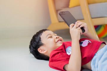 A cute little Asian boy smiling while communicates on a cell phone.