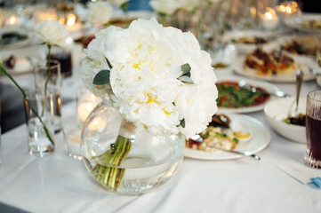 An incredibly beautiful wedding bouquet lies on the table during dinner.
