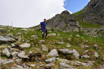 Exhausted hiker with backpack on a trail in the mountains