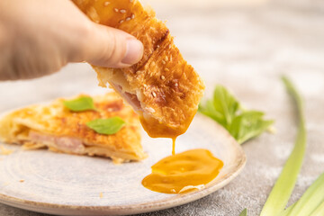 Fried homemade khachapuri cake with hand with cheese and meat, fried in pan. Side view, selective focus
