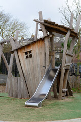 Children's eco playground. Little wooden house with a slide for children on the ecological playground on the summer day
