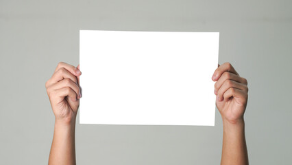 Close up of  men hands holding the white blank paper isolated on grey white background. Mockup for design 