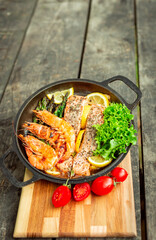 Healthy baked salmon steaks with greens and asparagus in a black cast iron skillet. A delicious low-carb breakfast.