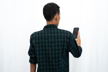 Back view of a man looking to the mobile phone that he hold