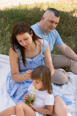 Fototapeta premium Mom, dad and daughter having fun on a picnic. Family vacation in nature