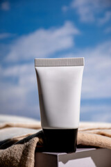 White sunscreen bottle on blue sky background. Sunscreen concept. Skin care concept. Copy space.