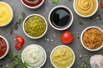 Many different sauces and spices on grey table, flat lay