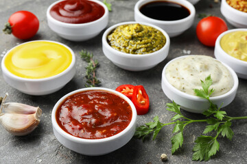 Many different sauces and spices on grey table, closeup