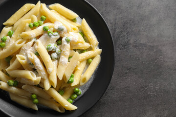 Delicious pasta with green peas and creamy sauce on grey table, top view. Space for text