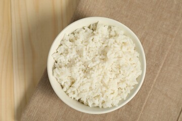 Delicious boiled rice in bowl on wooden table, top view