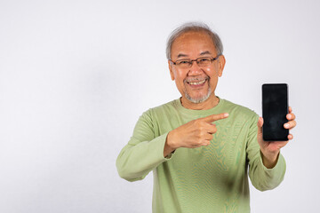 Portrait Asian smiling old man holding a cell phone and pointing to blank screen studio shot...