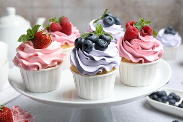 Tasty cupcakes with different berries on light grey table, closeup