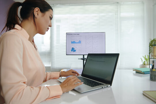 Marketing specialist working online with vlm model on laptop and developing project while sitting at her workplace in office