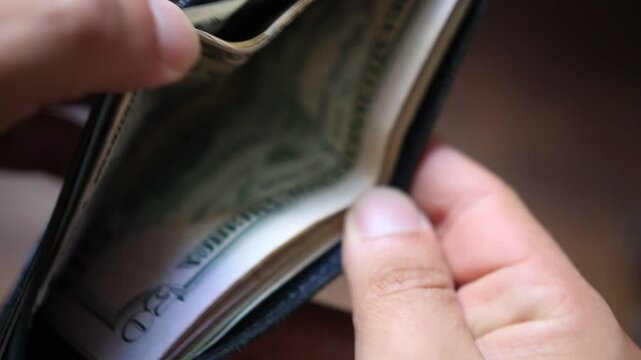 A man check for US dollar hundred bills on his leather wallet 