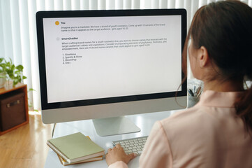 Rear view of young businesswoman using vlm model and reading information on computer monitor in...