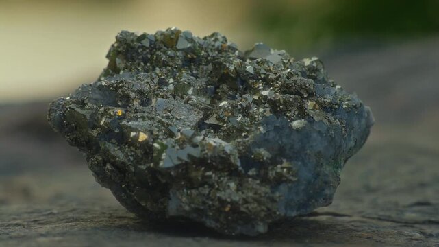 Close-up, large pyrite crystal lying on a rock with lake in the background