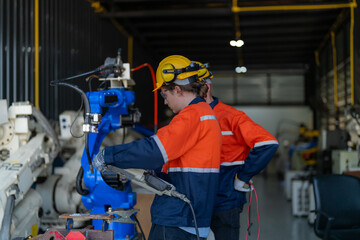 Fototapeta premium engineers check control heavy machine robot arm. Diverse Team of Industrial Robotics Engineers Gathered Around Machine. Professional Machinery Operators repair electric robot on bright digital panel.