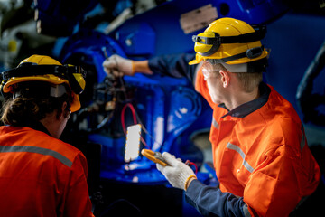 engineers check control heavy machine robot arm. Diverse Team of Industrial Robotics Engineers Gathered Around Machine. Professional Machinery Operators repair electric robot on bright digital panel.