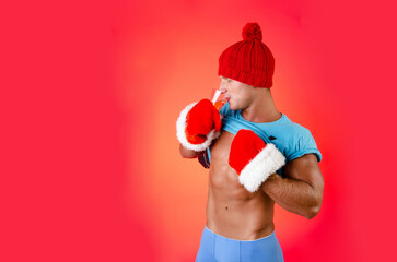 New Year's and Christmas. Handsome muscular man posing on a red background.