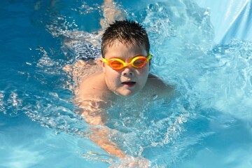 childhood joy during a sunny pool day, complete with orange goggles and a wide smile