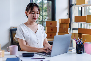 Portrait business woman smile and use tablet checking information on parcel shipping box before send to customer. Entrepreneur small business working at home. SME business online marketing.
