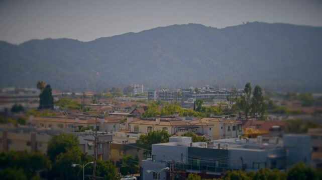 Panning shot of a city at the foot of the mountains on a summer day. Overlook of Glendale, California in summer heat mist. Suburban neighborhood of a warm southern city.