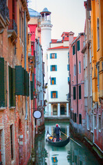 Venetian gondolier punting gondola through green canal waters of Venice Italy © muratart