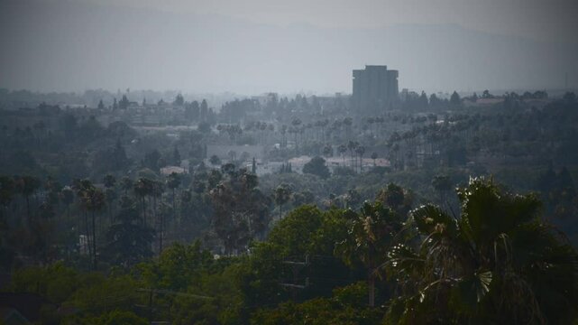 A view of a city at the foot of the mountains, in pale colors. Overlook of Glendale, California in twilight mist. Suburban neighborhood of a warm southern city.