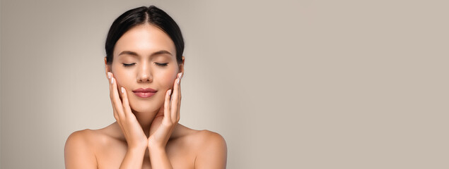 Calm positive pretty young european woman with perfect skin and closed eyes, touching hands to...