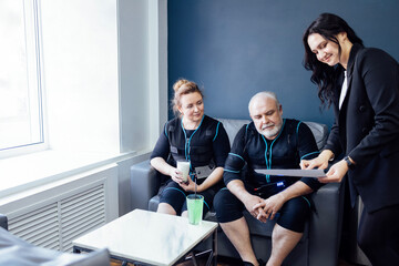 Fototapeta premium Secretary of fitness club offers elderly couple to choose workouts.