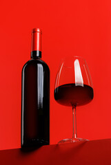 Red wine elegance: Wine glass and bottle against vibrant red background