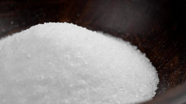 Coarse salt epsom for a relaxing bath and spa with magnesium in a wooden bowl close up. Wellness and body care ingredient. Rotation