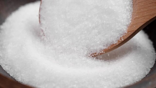 Epsom salt (Magnesium sulfate) crystals falling from wooden spoon close up. Relaxing spa ingredient