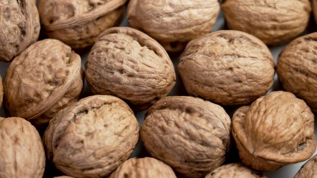 Unpeeled whole walnuts group with nut shells as a source of protein and fiber. Hard textured peel close up. Rotation