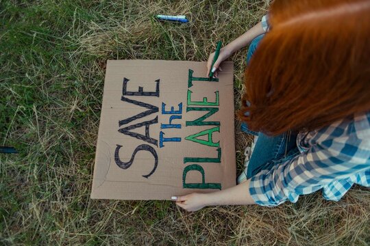 Teenage girl coloring alphabets of protest banner at public park