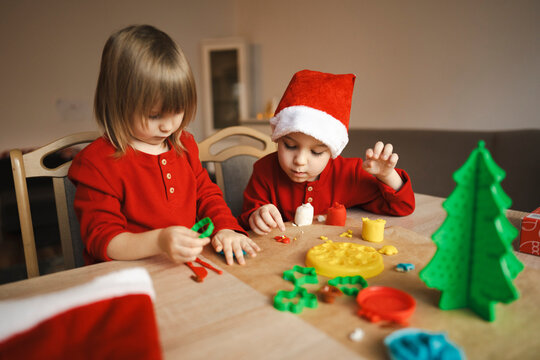 Siblings making plasticine Christmas tree decorations at home