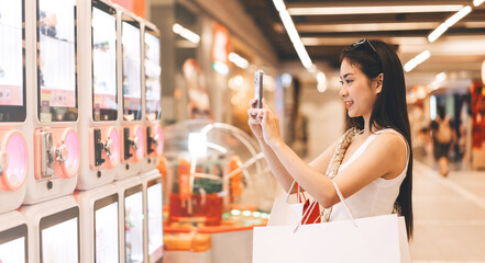 Young adult asian woman playing crane game indoors department store with copy space