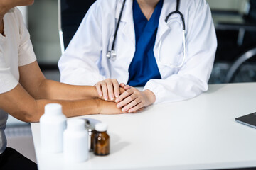 A young female nurse works at a desk with a grey-haired Asian mature woman, discussing heart-related conditions like heart disease, heart attack, and hypertension.