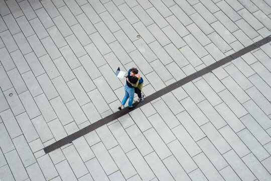 Colleagues embracing on paved footpath