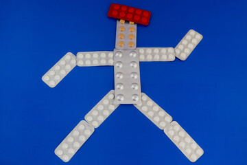 Figure of a human made from pill blisters on a blue background, vitamins for the body, comprehensive treatment, medication therapy, proper nutrition and diet