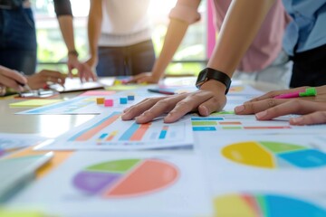 Group of people collaborating on charts and graphs, analyzing data and discussing strategies during a business meeting, emphasizing teamwork and productivity.