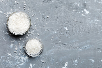 A wooden bowl of salt crystals on a wooden background. Salt in rustic bowls, top view with copy space