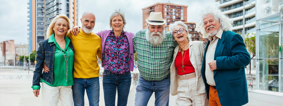 Happy elderly friends spending leisure time together in city