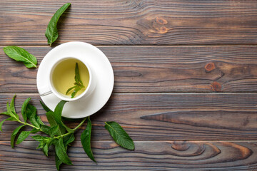 Cup of mint tea on table background. Green tea with fresh mint top view with copy space