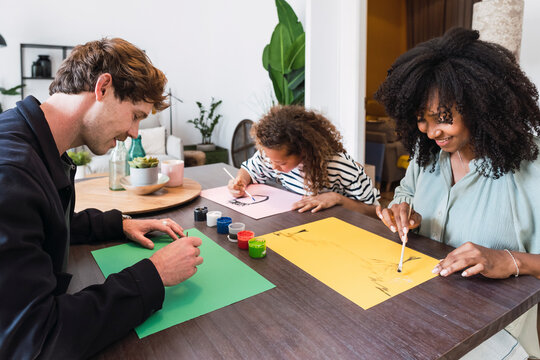 Family sitting at table drawing and painting together