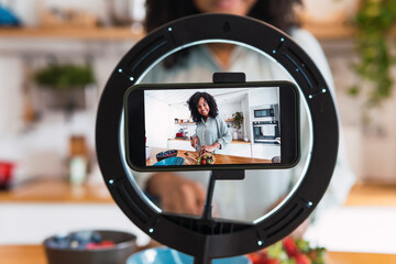 Woman standing in kitchen filming cooking tutorial