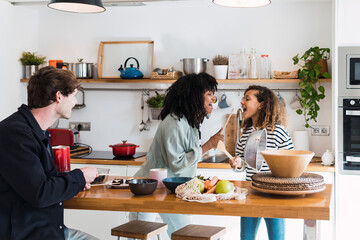 Happy family preparing food together singing and dancing in the kitchen