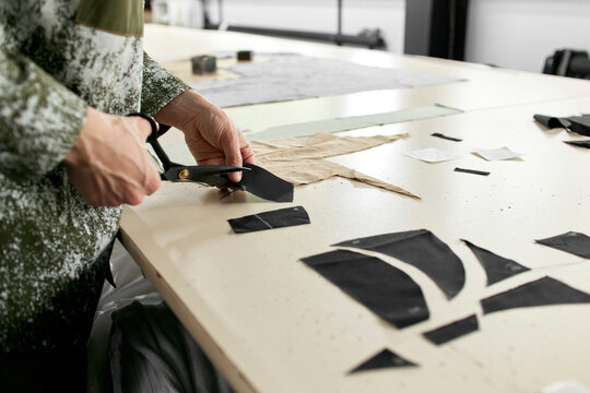 Fashion designer cutting piece of cloth at workshop