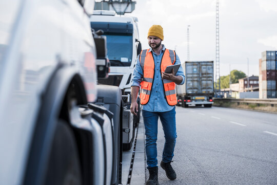 Truck driver examining truck on road