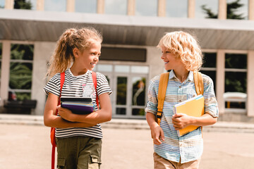 Boy and girl little pupils classmates schoolchildren students talking going back home from school...